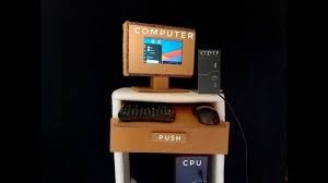 Een computerstation gemaakt van karton met een scherm, toetsenbord, muis en CPU.