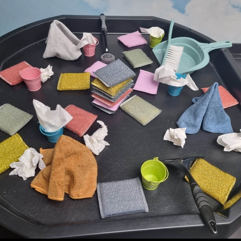 Een zwart bakje met verschillende schoonmaakdoeken en een paar emmers is zichtbaar.
