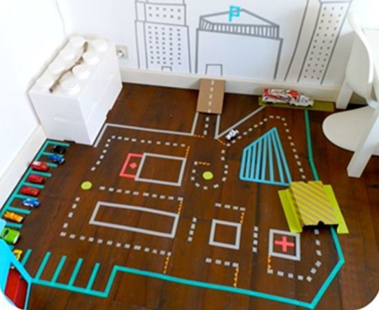 Een kleurrijk speelkleed met wegen en parkplaatsen, omringd door speelgoedauto's en decoratieve elementen.