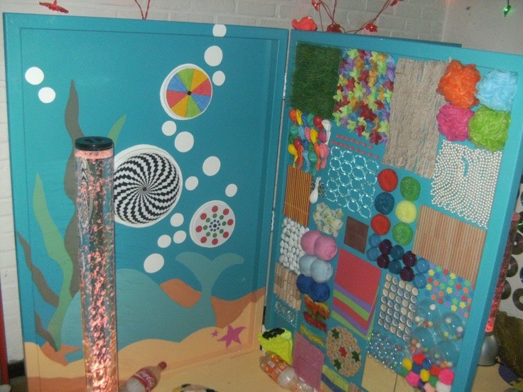 Een kleurige, creatief versierde muur met bollen, texturen en een lichtgevende buis aan de onderkant.