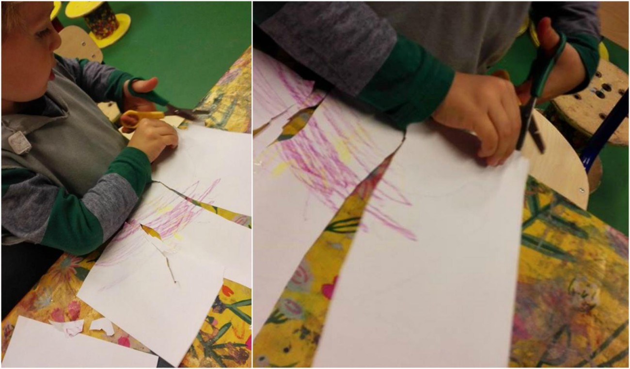 Een kind knipt met scharen in papier dat lichtkleurig is en met kleurpotlood is beschreven.