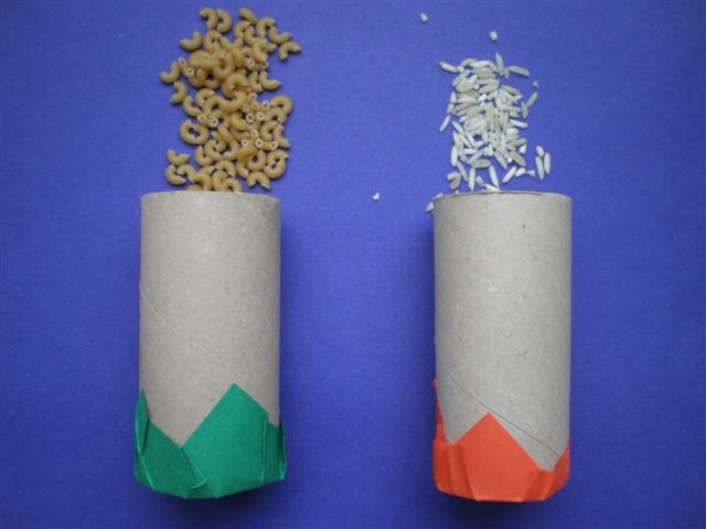 Twee lege kartonnen rolletjes met groene en oranje decoratie onderaan, links met pasta en rechts met rijst.